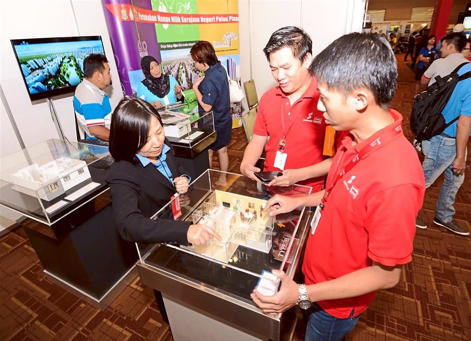 For the average citizen: (From left) PDC Properties Sdn Bhd sales admin executive Mary Loo telling visitors Leong Jee Yung and Lee Yau Chong all about the state’s affordable housing projects.